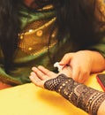 A female artist checks mehandi or henna design on female hand.
