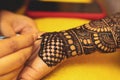 An artist performing mehandi or henna design on female hand