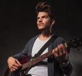 Artist playing guitar in studio background while looking away Royalty Free Stock Photo