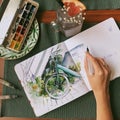 The artist`s hand paints a watercolor bike