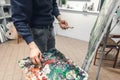 Artist`s hands with brushes and a palette knife, painted on canvas, mixes paint on pallets. Painter paints a picture in an art Royalty Free Stock Photo