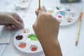 Artist`s hands are mixing water colors