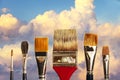 Artist`s paintbrushes against a background of clouds