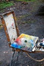The artist`s palette with brushes in a box is on the street, ready to work. Selective focus