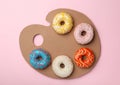 Artist`s palette made with donuts and cardboard on pink background, top view