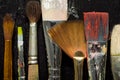 Artist`s tools, brushes in paint are in a row on a black wooden background. Royalty Free Stock Photo