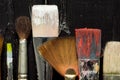 Artist`s tools, brushes in paint are in a row on a black wooden background. Royalty Free Stock Photo