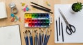 An artist\'s workspace featuring a set of watercolor paints with a range of colors, three black pencils, Royalty Free Stock Photo