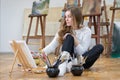 Artist sits on the knees on the floor in art studio and paints Royalty Free Stock Photo