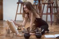 Artist sits on the knees on the floor in art studio and paints Royalty Free Stock Photo