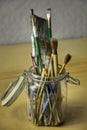 Glass jar of used artist brushes in variety of shapes and sizes.