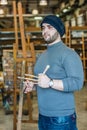 Artist/teacher holding brushes and looking at his artwork Royalty Free Stock Photo