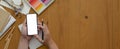 Artist using blank screen smartphone while working on wooden worktable Royalty Free Stock Photo