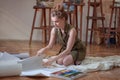 Artist woman sits on the floor and select papers for paints Royalty Free Stock Photo