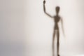 An artist wooden model standing up waving it`s hand. Shot through a semi transparent material. Creating a textured, blurred