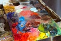 Artist wooden palette, mess of fresh bright colorful oil paints mixed in disorder, outdoor painting plein air Royalty Free Stock Photo