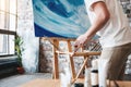 Artist work in art studio near easel with canvas. Painter paints a painting with oil paints in loft studio. Drawing workshop