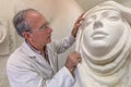 Artist at work in studio on a sculpture of face Royalty Free Stock Photo