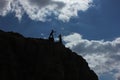 Artistic angel figure and figurine silhouette on top of high mountain rock. Help or fight statue.