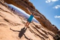 Artistic angle of a beautiful fit attractive woman standing with arms out at Mesa Arch in Canyonlands National Park