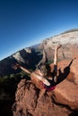 Artistic angle of a woman sitting on the top of Observation Point in Zion National Park with arms raised. Concept for