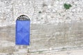 An artistic blue steel door set in an ancient grey stone wall.