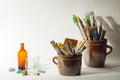 Artistic brushes colorful nice stones old bottles and painting tools in old ceramic pots on a white background