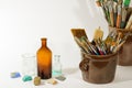 Artistic brushes colorful nice stones old bottles and painting tools in old ceramic pots on a white background