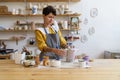 Artistic ceramist girl master at work: happy woman in apron holding handmade jug in ceramics studio Royalty Free Stock Photo