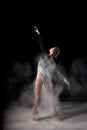 Artistic dance pose using powder or dust. Beautiful expressive ballet dancer in dust