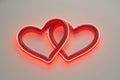 An artistic digital rendition of a neon sign featuring two interlinked hearts, glowing in a deep red hue for Valentine's Day