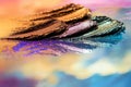 Artistic display of smudged metallic eyeshadow pigments creates a vibrant visualization on a reflective surface