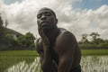 Young attractive contemporary ballet dancer and choreographer , a black African American man dancing and posing on tropical rice Royalty Free Stock Photo