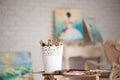 Artistic equipment: easel, paint brushes, tubes of paint, palette and paintings on work table in a artist studio Royalty Free Stock Photo