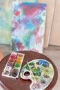 Artistic equipment in studio, easel, paintbrushes, tubes of paint, palette and paintings on work artist table.painting Royalty Free Stock Photo