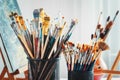 Artistic equipment in studio: painting, easel, paintbrushes and paints.