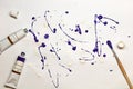 Artistic expression. Blots of purple and white paint on a sheet of paper with a brush and oil color tubes lying near it. Royalty Free Stock Photo