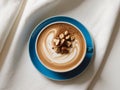 artistic latte coffee with hazelnut topping and blue ceramic saucer flat lay. Royalty Free Stock Photo