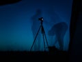 Artistic long exposure photo of a photographer in action. Multiple silhouettes and a camera un tripod. Royalty Free Stock Photo