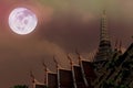 Artistic Nighttime Photo of Thai Temple and Full moon and dramatic sky and clouds.