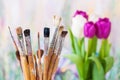 Artistic paintbrushes, bouquet of tulips and painting