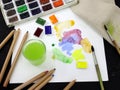 Watercolor paints in a plastic container and colored paint strokes on a sheet. Royalty Free Stock Photo