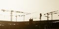 Artistic panorama view silhouette group of tower cranes working on construction site. Royalty Free Stock Photo