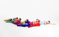 Artistic performance. Young girls, ballet dancers in multicolored bright clothes dancing, lying on floor against grey
