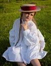 Artistic photo of a girl with pigtails and a hat sitting on the grass. Portrait of a girl in a straw hat. Summer photo. Royalty Free Stock Photo