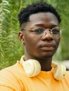 Artistic portrait of a serious young african american man with headphones among the greenery Royalty Free Stock Photo