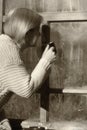 Artistic portrait of a woman looking out of the window to the street. He holds a mug with a drink in his hand