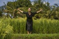 Artistic portrait of young attractive and happy Asian woman outdoors at green rice field landscape dancing and doing relaxation Royalty Free Stock Photo
