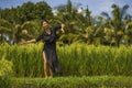 Artistic portrait of young attractive and happy Asian woman outdoors at green rice field landscape dancing and doing relaxation Royalty Free Stock Photo