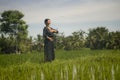 Artistic portrait of young attractive and happy Asian woman outdoors at green rice field landscape dancing and doing spiritual Royalty Free Stock Photo